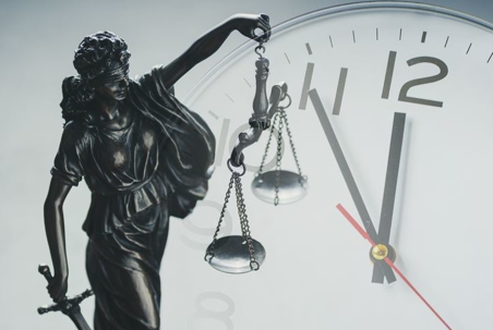 Lady Justice holding scales in front of analog clock