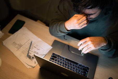man looking stressed in front of a laptop