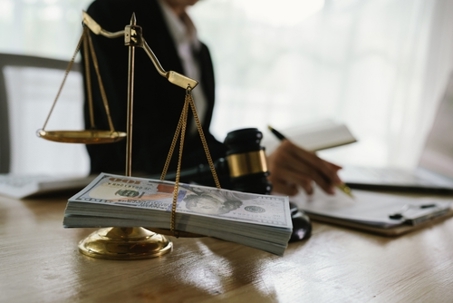 A hand holding stacks of money is shown being exchanged with another hand, implying a transaction, payment, or perhaps an illegal exchange in a legal context.